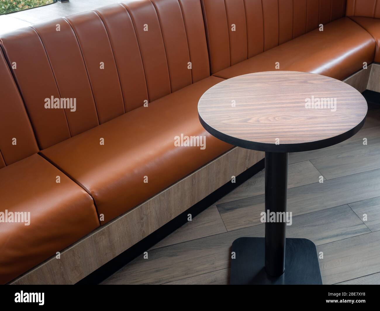 Decoración de muebles en estilo café retro. Mesa de bar vacía de madera  redonda y sofá de cuero naranja en el suelo de madera con luz natural  Fotografía de stock - Alamy