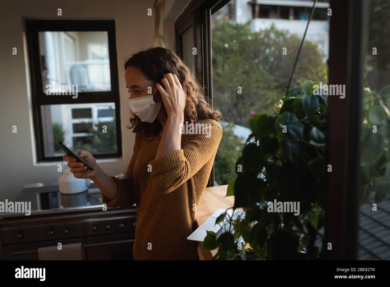 Mujer que lleva una máscara en casa. Distanciamiento social en cuarentena durante la epidemia de coronavirus Foto de stock