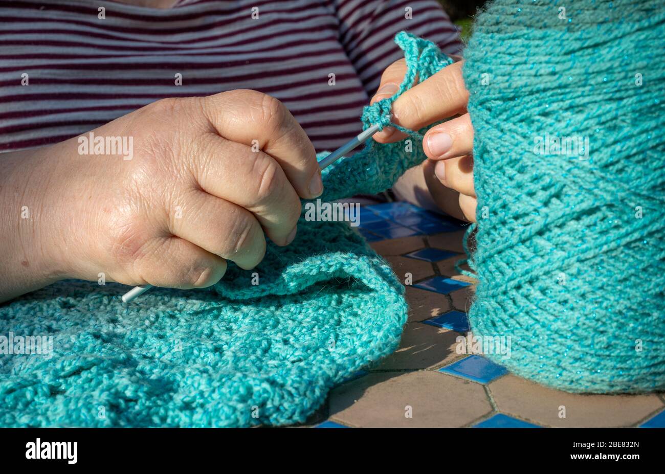 mujer haciendo un chal azul o bufanda con gancho de ganchillo en el jardín  en casa. hobby o pasatiempo., pasando el tiempo Fotografía de stock - Alamy