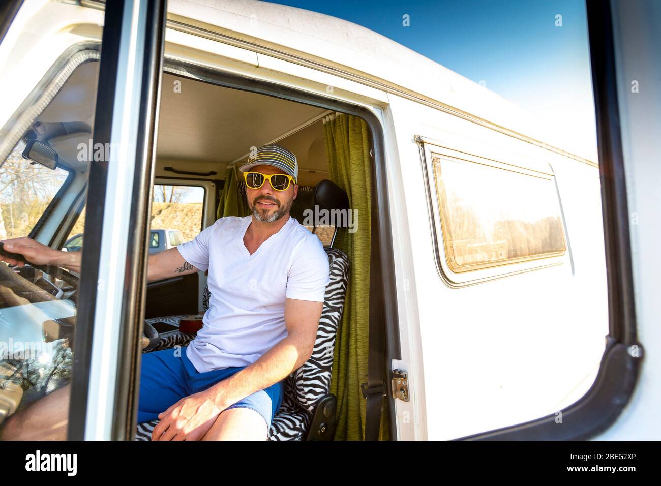 Retrato de un hombre con gafas de sol durante las vacaciones en su furgoneta Foto de stock