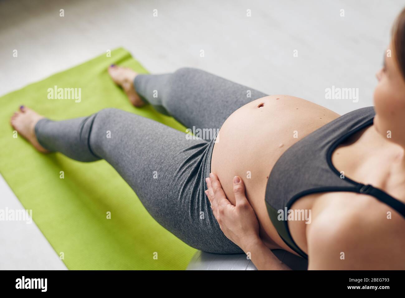 Vista superior de una mujer embarazada apoyada en una pelota de yoga y haciendo ejercicio de relajación para la espalda Foto de stock