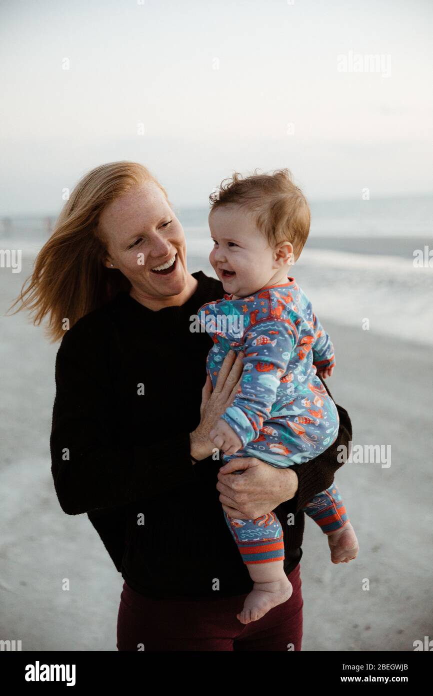 la madre joven y el niño niño chubby sano sonreirán durante el paseo por la playa Foto de stock