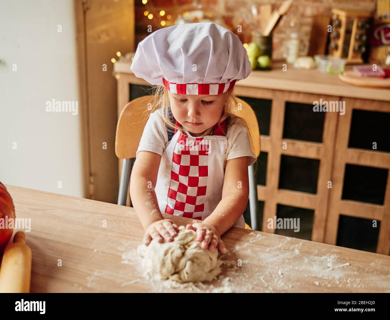 A la ni a cocinando ropa de chef le gusta amasar la masa. Ni as en