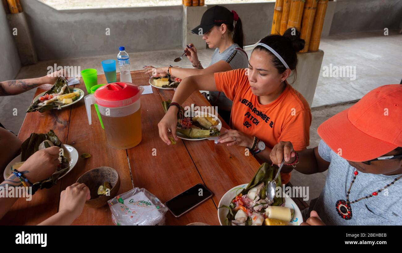 Grupo de turistas que comen maitos de pescado en la comunidad Cofan Dureno Millennium Foto de stock