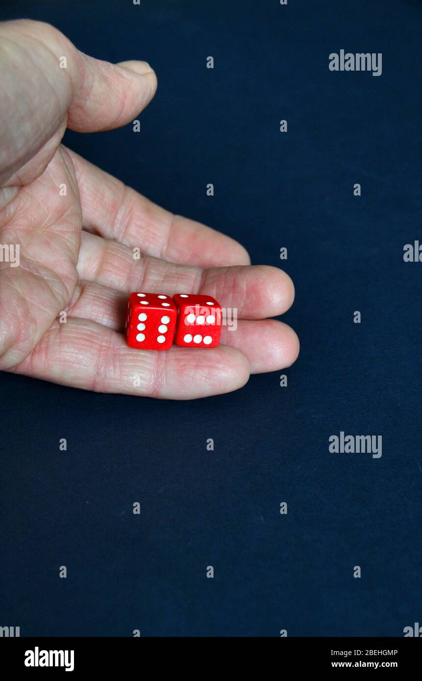 Una mano abierta que sostiene dos dados rojos con ambos mostrando seis. Foto de stock