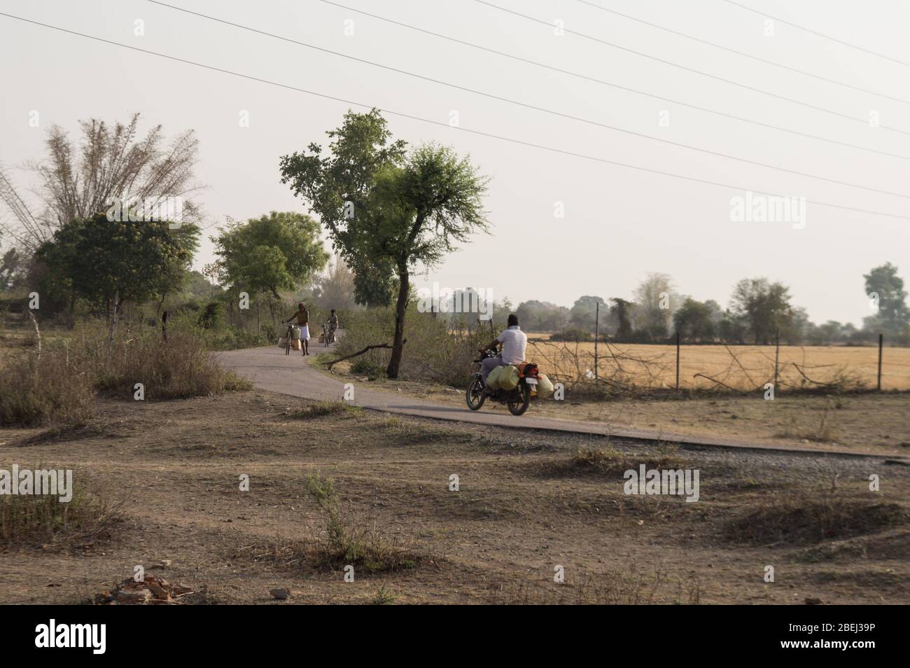 Los aldeanos indios van a recoger agua de cerca de estanque, pero hay una diferencia entre estos dos que es uno que tiene motocicleta que es más Foto de stock