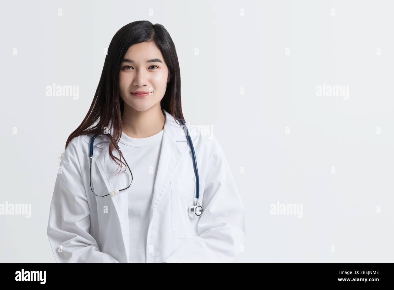Atractiva doctora asiática mirando cámara con cara sonriente, aislada sobre fondo blanco con espacio de copia. foto de estudio Foto de stock