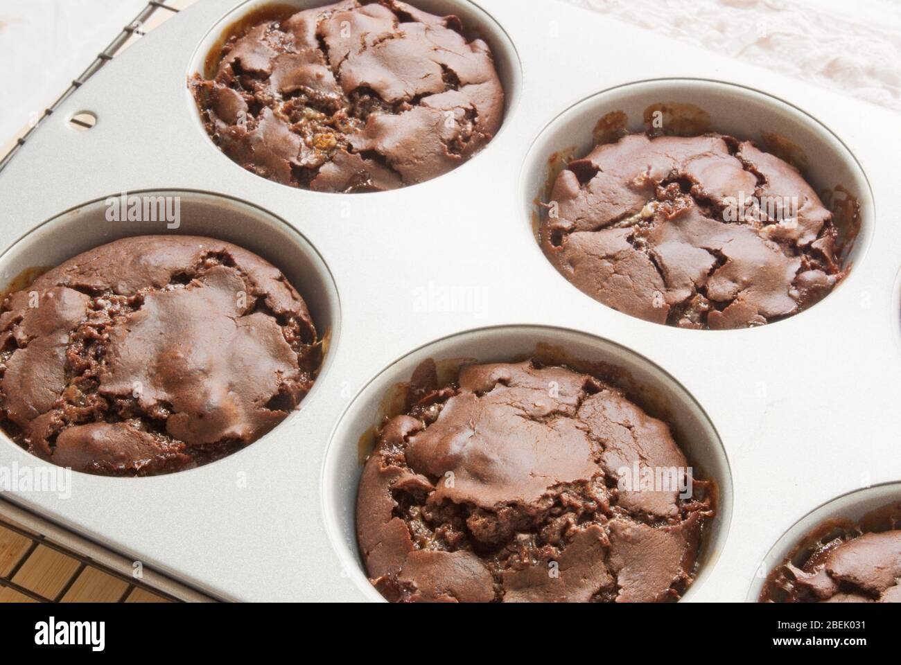 Magdalenas de chocolate con malvavisco en molde para hornear en una rejilla de refrigeración de la cocina. Grabado con luz natural. Foto de stock