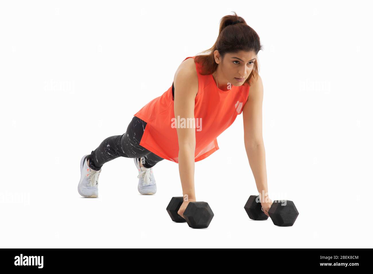Mujer haciendo pushups con pesas sobre un fondo blanco. Foto de stock