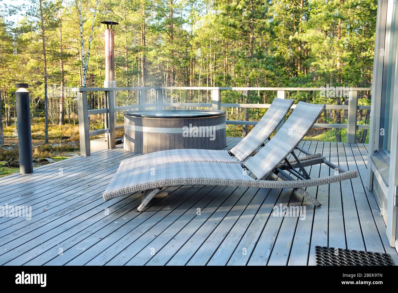 Chapoteo Verter ecuador Bañera de hidromasaje tradicional finlandesa de madera y dos chaise longues  en una terraza con fondo de bosque Fotografía de stock - Alamy