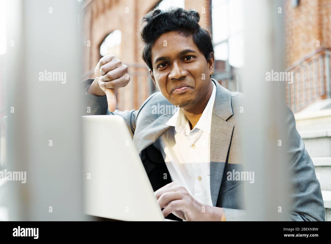 Joven apuesto hombre indio en una camisa blanca y un traje de negocios está sentado Foto de stock
