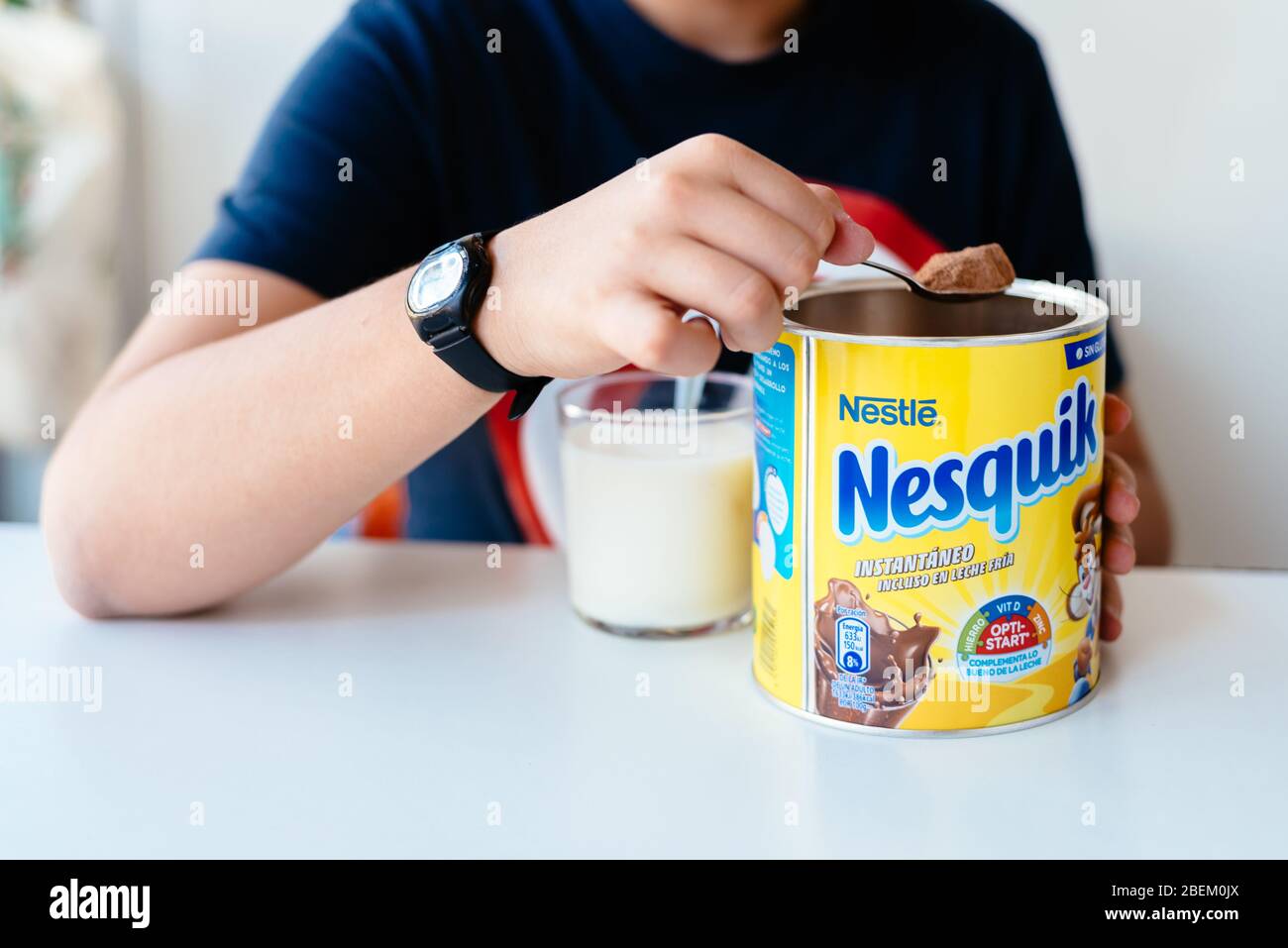 Madrid, España - 1 de abril de 2020: Niño que sirve cacao en polvo Nesquik  en un vaso de leche. Nesquiq es una Marca comercial de Nestlé Fotografía de  stock - Alamy