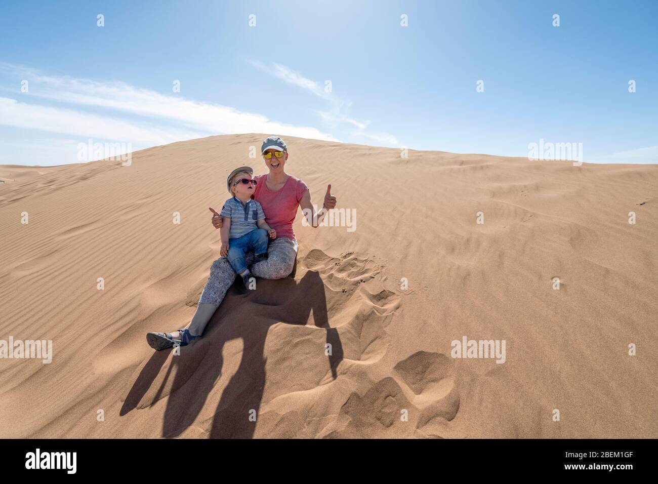 Madre y su hijo de 2 años disfrutando sentado en las dunas de arena del Sahara, Marruecos, África Foto de stock
