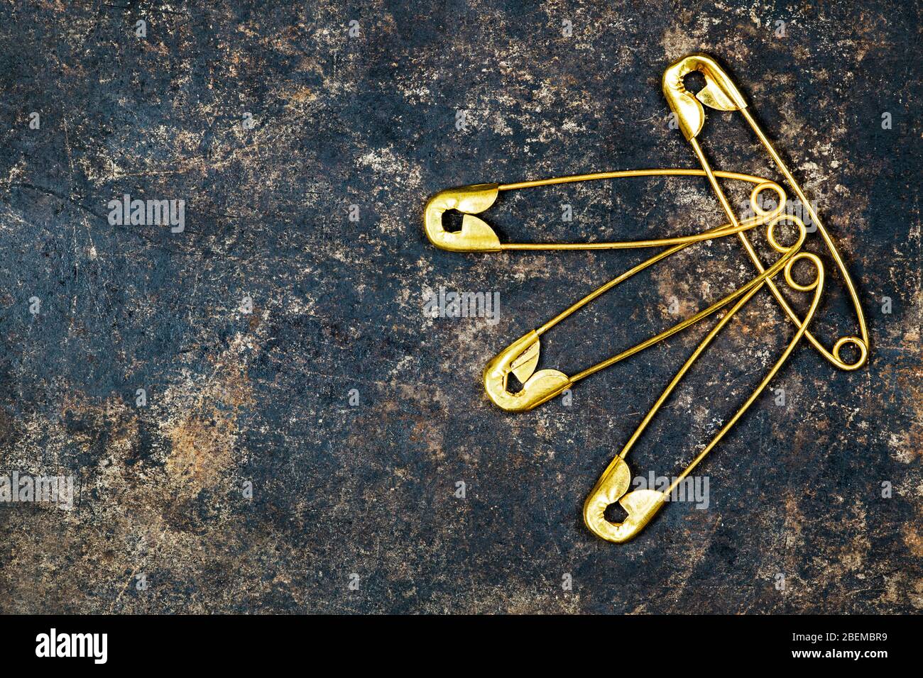 Concepto de relación humana, grupo de pines de seguridad de oro conectados sobre fondo metálico oxidado Foto de stock