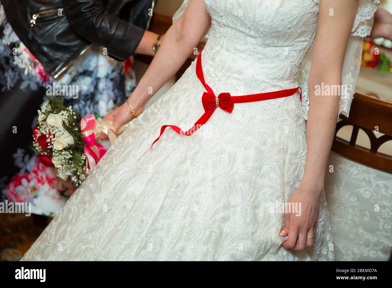 Novia en vestido blanco con cinta roja . Cinta en el vientre de la novia  Fotografía de stock - Alamy