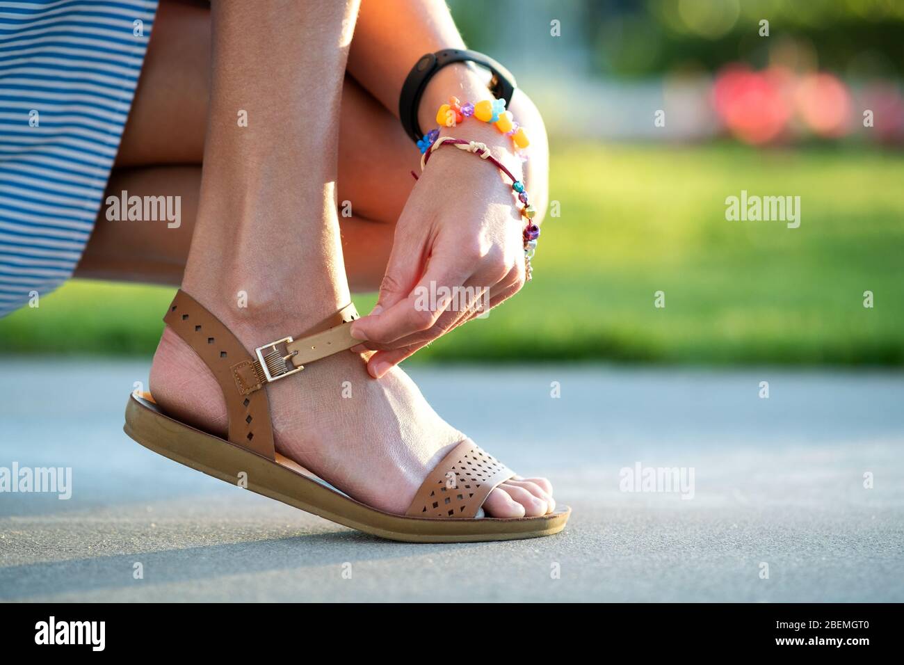 Primer plano de las manos de la mujer atando sus sandalias abiertas de  verano zapatos en la acera en tiempo soleado Fotografía de stock - Alamy