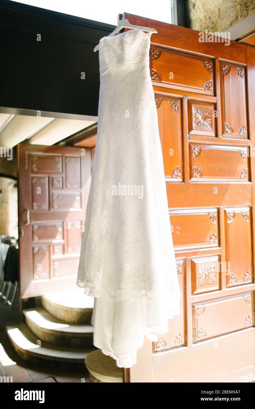 Un vestido blanco de boda colgado en el perchero. Preparativos para el día de la boda. Foto de stock