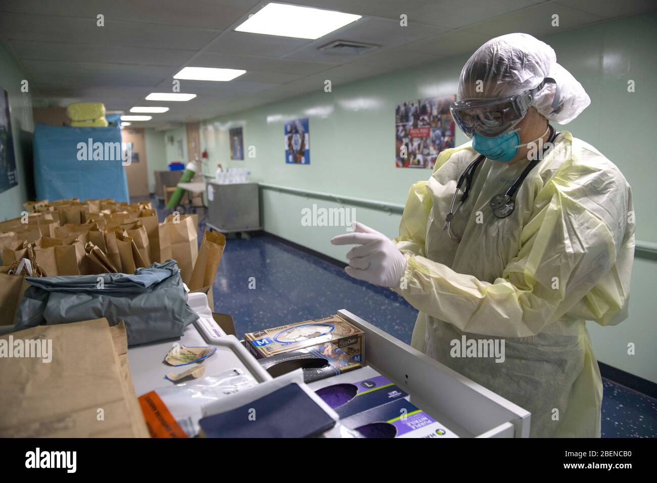 NUEVA YORK (13 de abril de 2020) Cmdr. Nelle Linz utiliza equipo de protección personal antes de entrar en la unidad de cuidados intensivos para tratar a los pacientes a bordo del buque del Hospital Military Sealift Command USNS Comfort (T-AH 20). Comfort cuida a los pacientes de trauma, emergencia y atención urgente sin tener en cuenta su estado COVID-19. Comfort está trabajando con Javits New York Medical Station como un sistema integrado para aliviar el sistema médico de la ciudad de Nueva York, en apoyo del apoyo de Defensa de las autoridades Civiles del comando Norte de los Estados Unidos como respuesta a la pandemia de COVID-19 Foto de stock