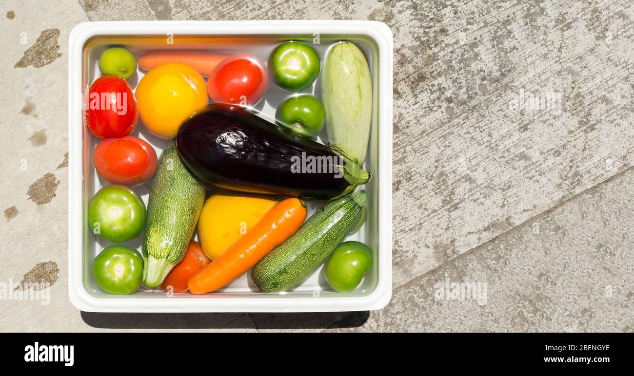 Lavado de frutas y verduras en agua jabonosa para desinfección con coronavirus. Foto de stock