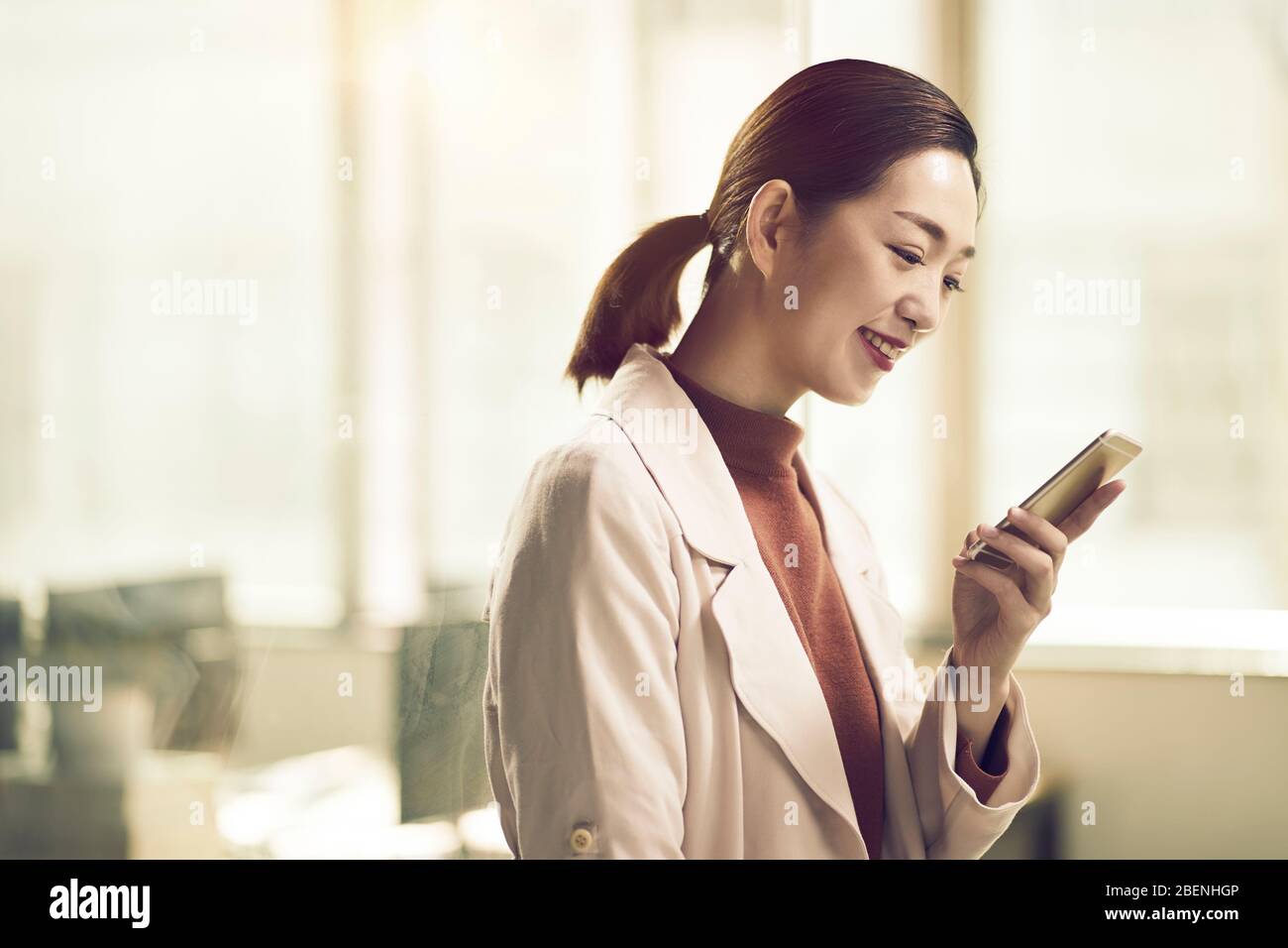 joven empresario asiático de negocios comprobando mensajes de texto utilizando el teléfono móvil Foto de stock