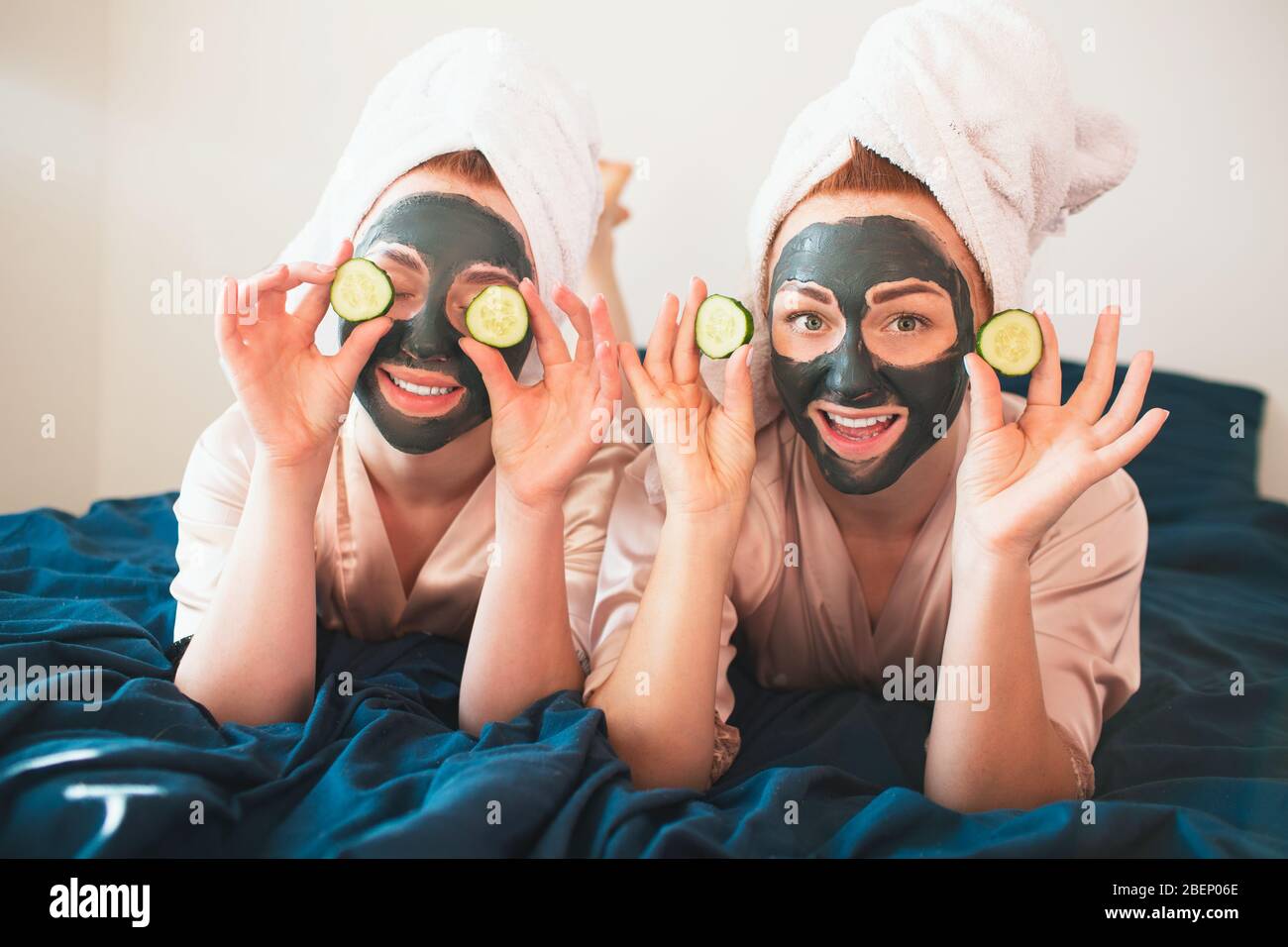 Dos modelos hacen máscara facial y usan pepino verde fresco. Dos jóvenes en y pijamas tienen una divertida fiesta en el juntos en casa Fotografía de stock - Alamy