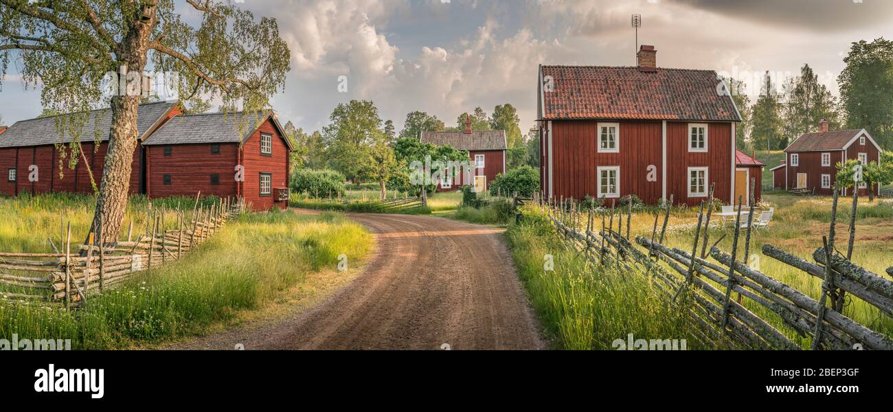Pequeño camino rural y antiguas casas tradicionales rojas en un paisaje rural en el pueblo de Stensjo by. Oskarshamn, Smaland, Suecia, Escandinavia Foto de stock