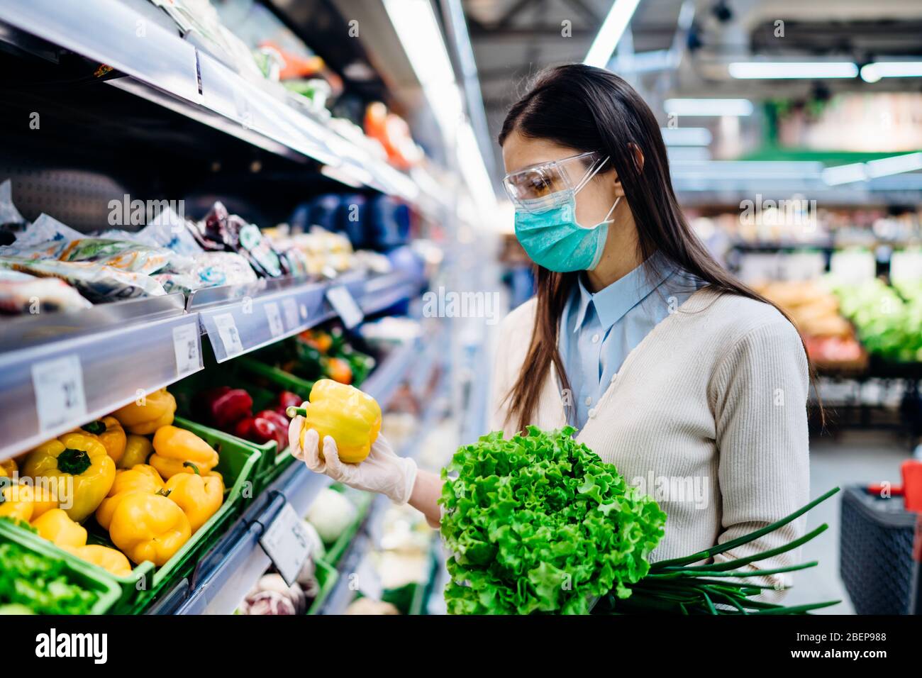 Mujer con máscara higiénica compra en supermercado tienda de comestibles para los verdes frescos, compras durante la pandemia.Fuente natural de vitaminas y minerales.Pla Foto de stock
