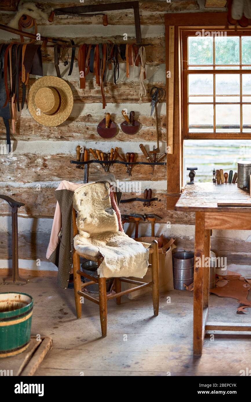 Imagen de un antiguo taller de calzado con un banco de trabajo de madera con zapatos de cuero y herramientas antiguas Foto de stock