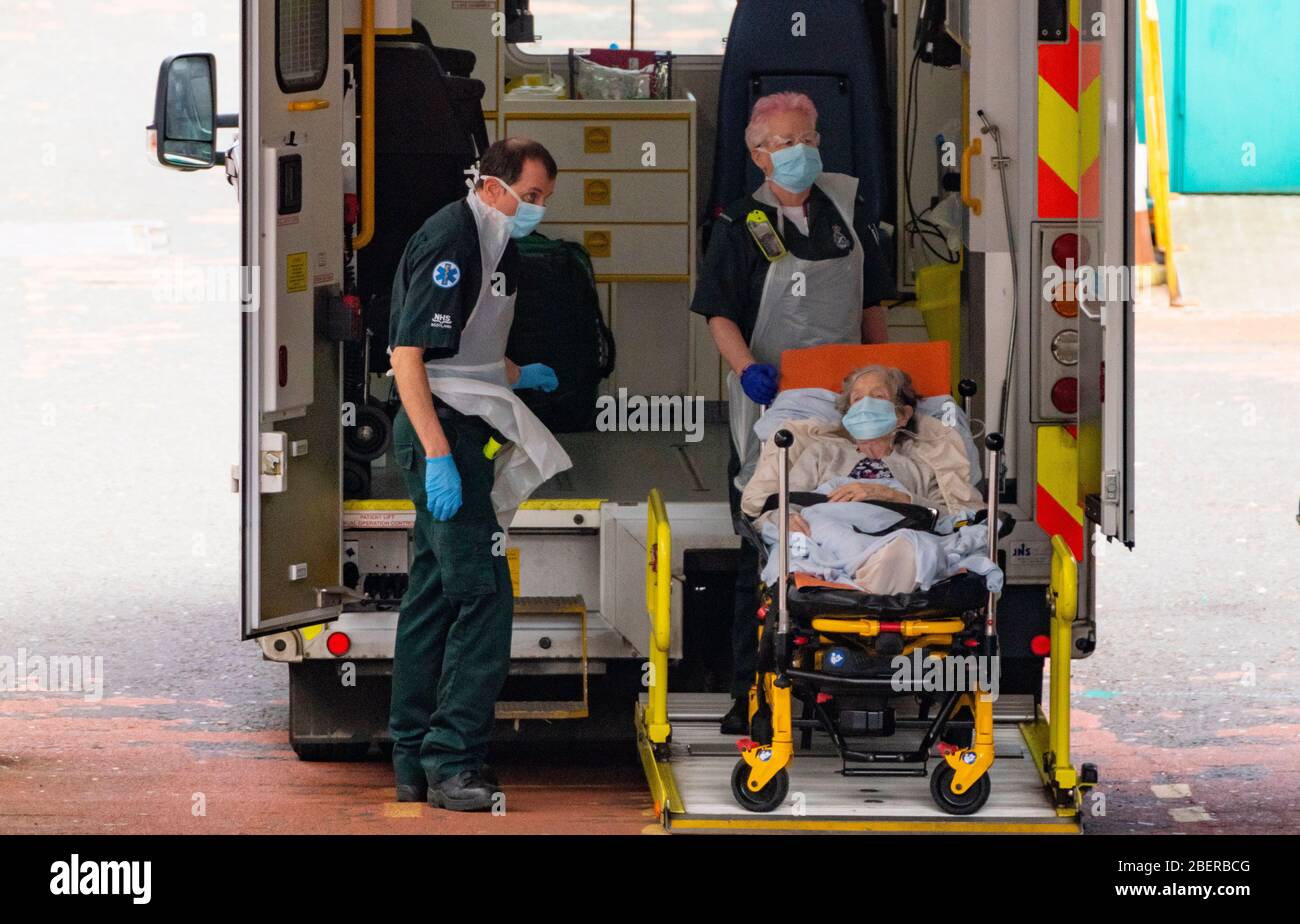 Glasgow, Escocia, Reino Unido. 15 de abril de 2020. El personal que lleva el EPI del departamento DE A&E de Glasgow Royal Infirmary descarga a un paciente mayor de una ambulancia. Iain Masterton/Alamy Live News Foto de stock