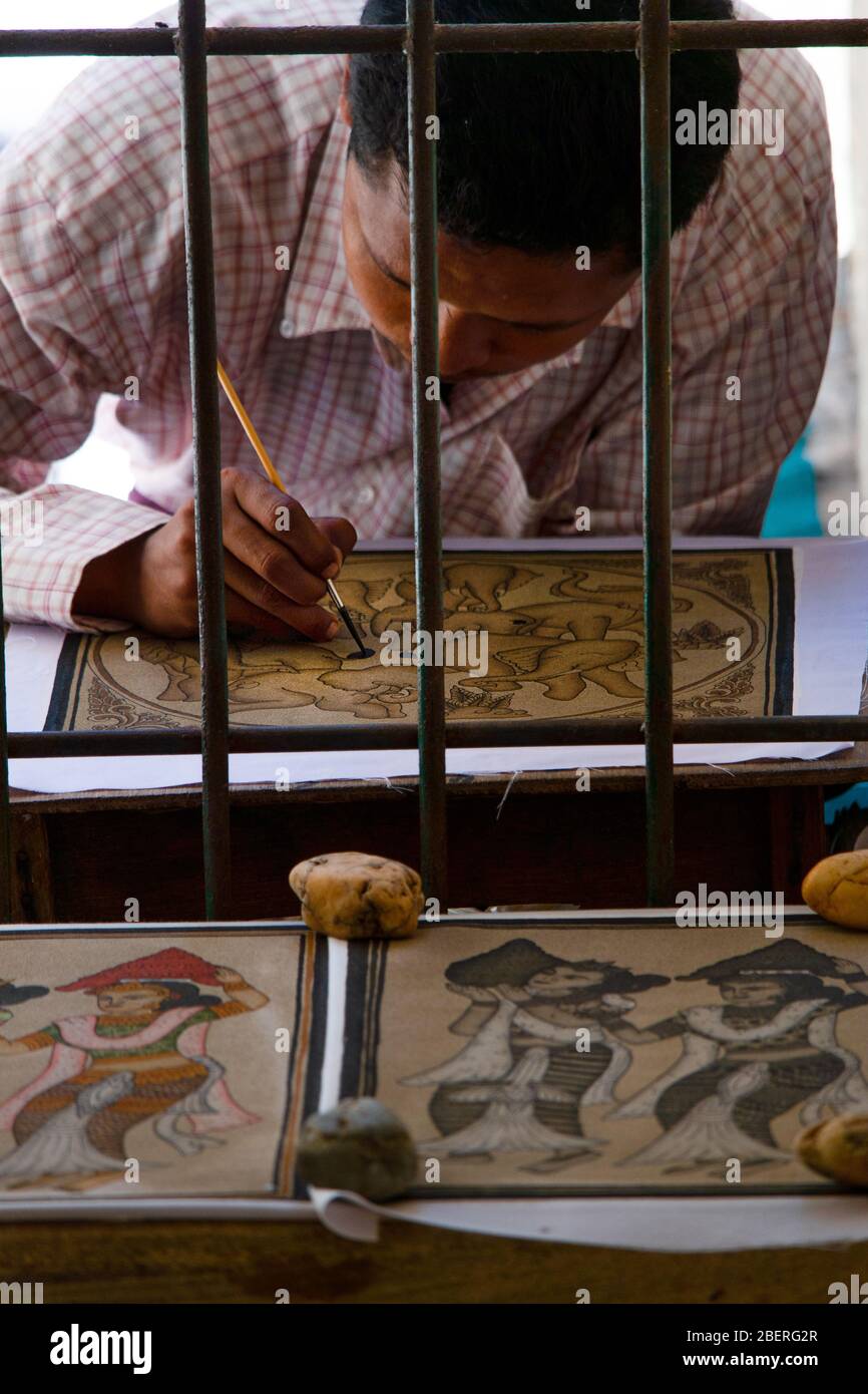 Los lugareños venden pinturas de seda pintadas a mano a través de ventanas de barra de metal de los templos de Bagan, Myanmar. Foto de stock