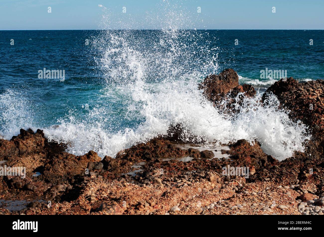 olas rompiendo en el mar hermoso con olas rompiendo en la orilla de piedra Foto de stock