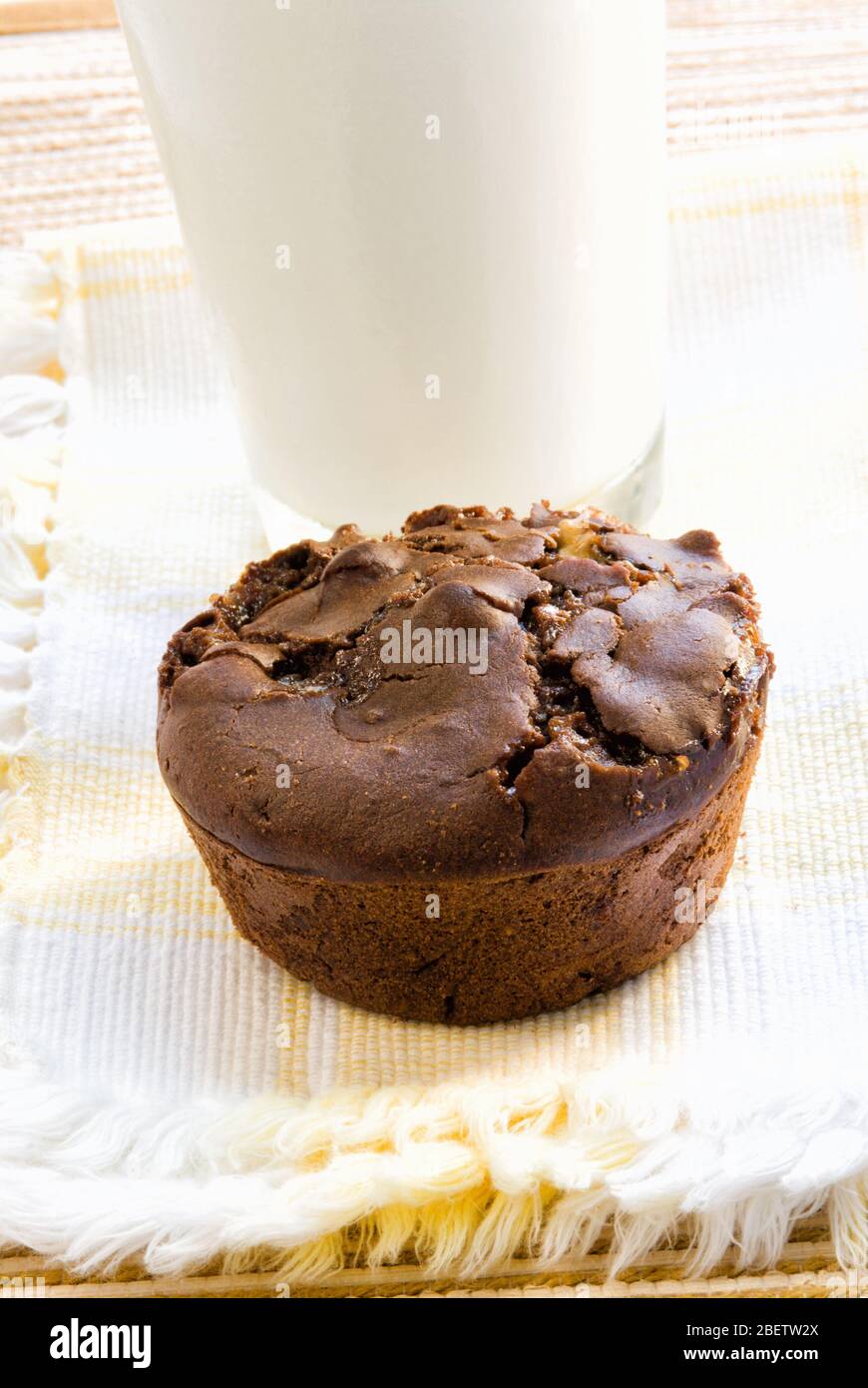 Un muffin de malvavisco de chocolate negro tamaño jumbo servido con un vaso de leche blanca fría. Foto de stock