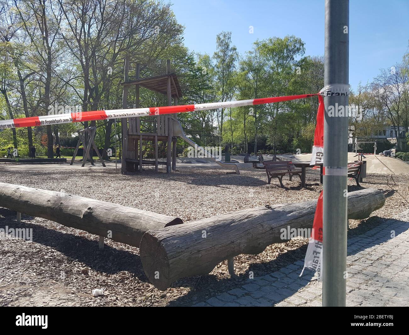 Parque infantil vacío, abandonado o campo de juegos en el parque o bosque con el tobogán cerrado con cinta de advertencia de barrera policial debido al virus corona covid-19 Foto de stock