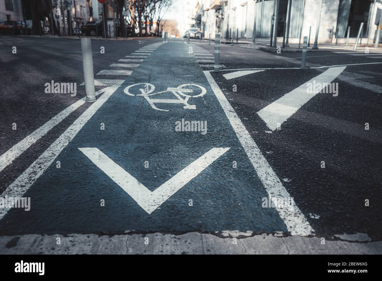 Vista de gran angular de una carretera urbana moderna con señal de bicicleta en un asfalto azulado y un cruce peatonal en una distancia, postes de plástico en el para Foto de stock