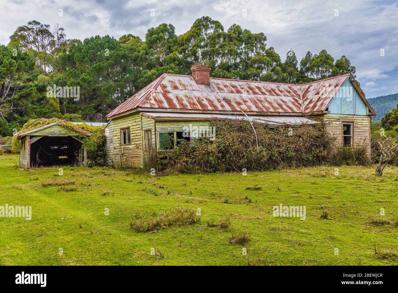 Una granja de colonos pioneros abandonada en una ladera a lo largo de la costa este de Tasmania en Australia. Foto de stock