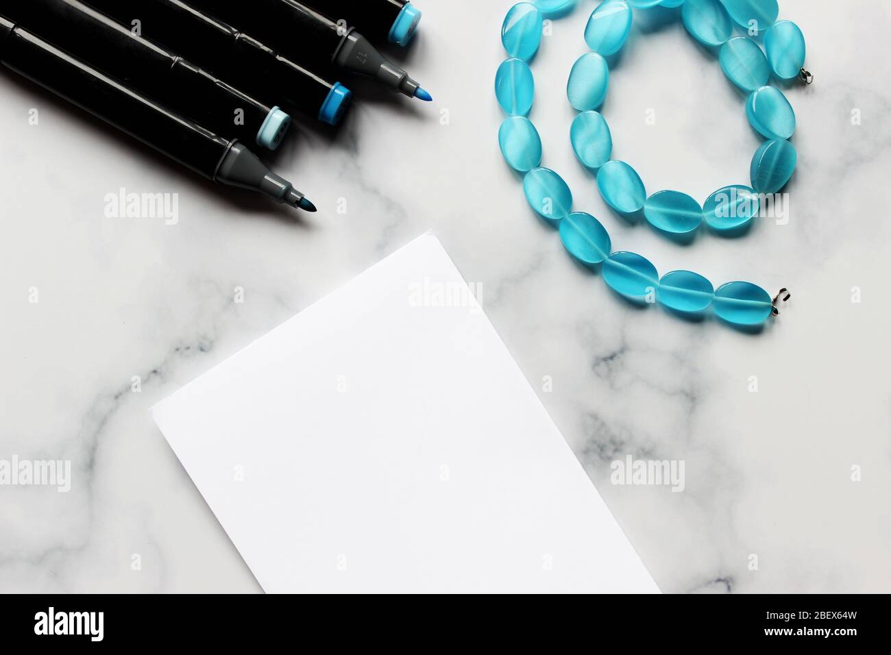 Fondo de mármol. Marcadores de sombras azules y una hoja de papel. Hoja para notas, tema azul. Notas de chicas y cuentas azules. Coloque para insertar texto Foto de stock