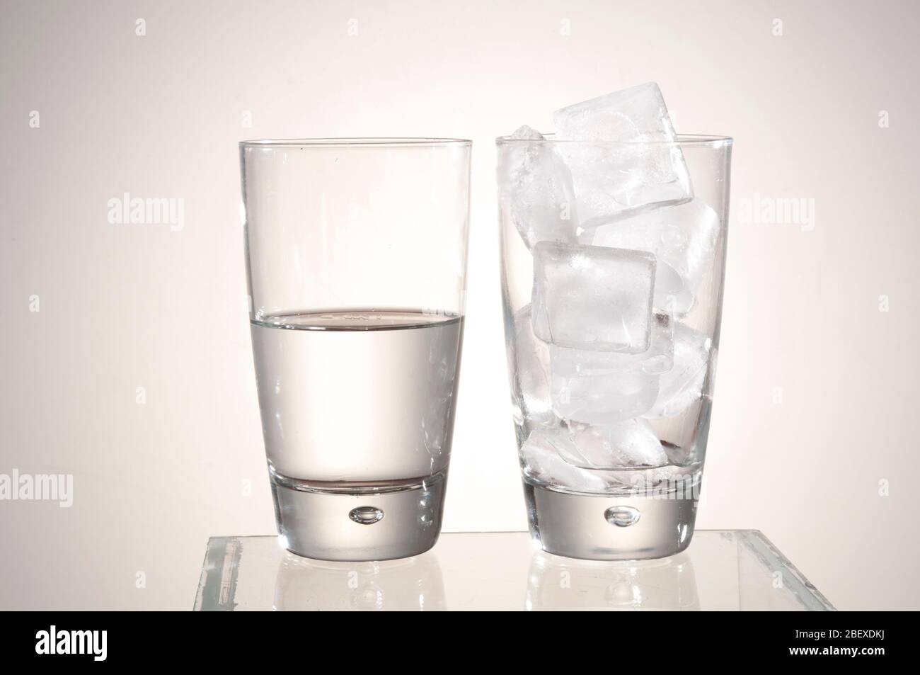 El concepto de fusión de hielo muestra que un vaso lleno de hielo se derrite para ser menos agua en el otro vaso. Foto de stock