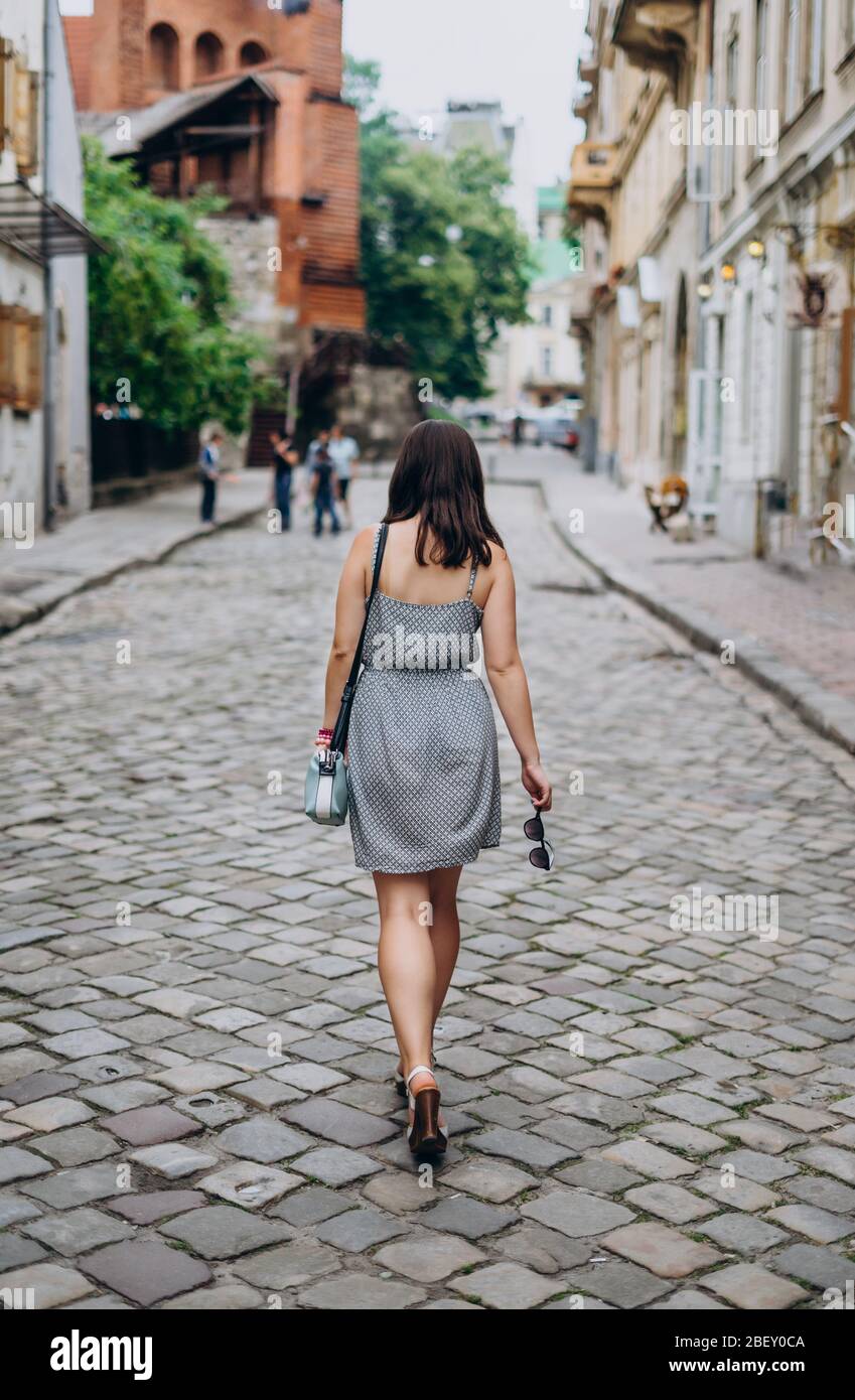Estilo de moda retrato de joven bella mujer elegante en vestido negro  caminando por las calles de la ciudad Fotografía de stock - Alamy