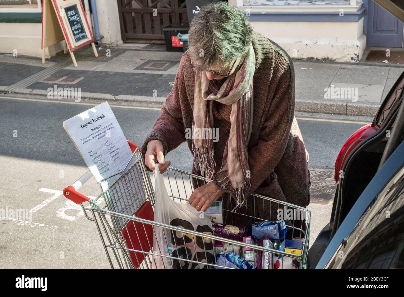 En la calle alta en Presteigne, Powys. Un voluntario que recoge provisiones donadas para el banco local de alimentos en la cercana Knighton, Powys, Gales, Reino Unido Foto de stock