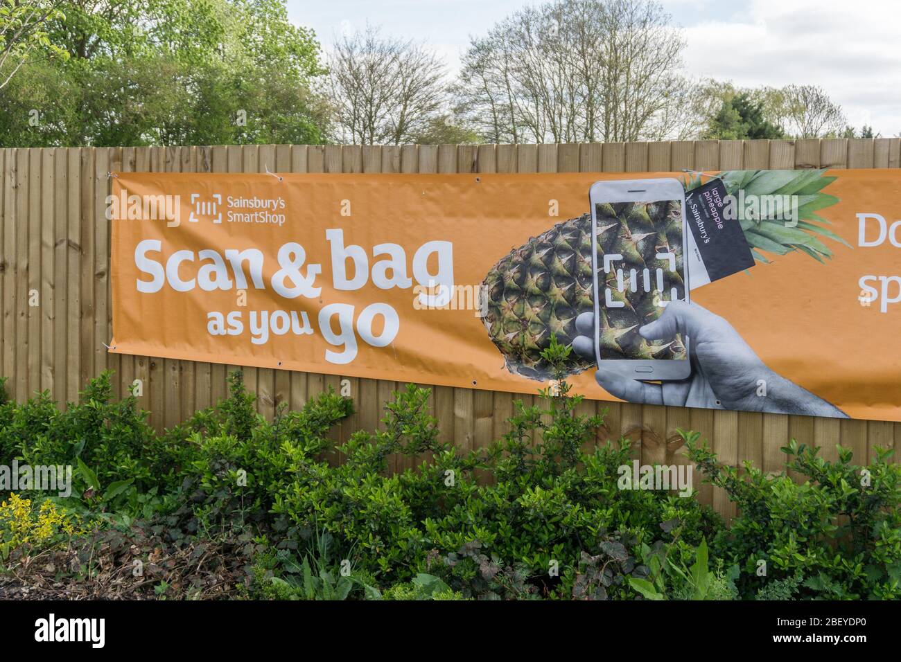 Escanee y haga su equipaje mientras se desplaza el anuncio en el aparcamiento, Sainsbury's, Olney, Buckinghamshire, Reino Unido Foto de stock