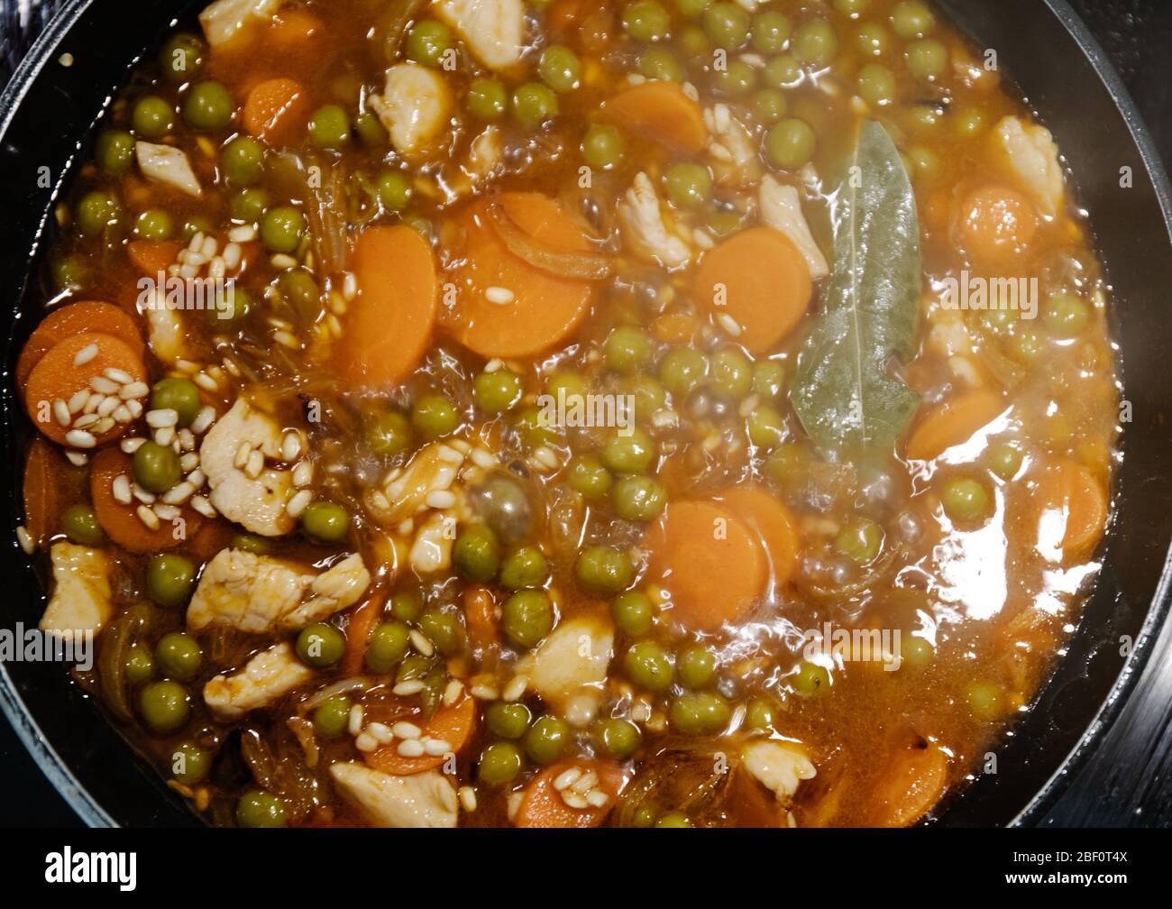Vista superior de una sartén cocinando una paella de arroz y pollo en España durante el confinamiento Foto de stock