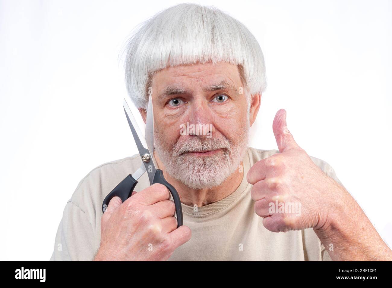 Un tiro horizontal de un hombre de cabello gris que ha estado en cuarentena demasiado tiempo finalmente aprueba el corte de pelo que se entregó con un pulgar hacia arriba. Foto de stock