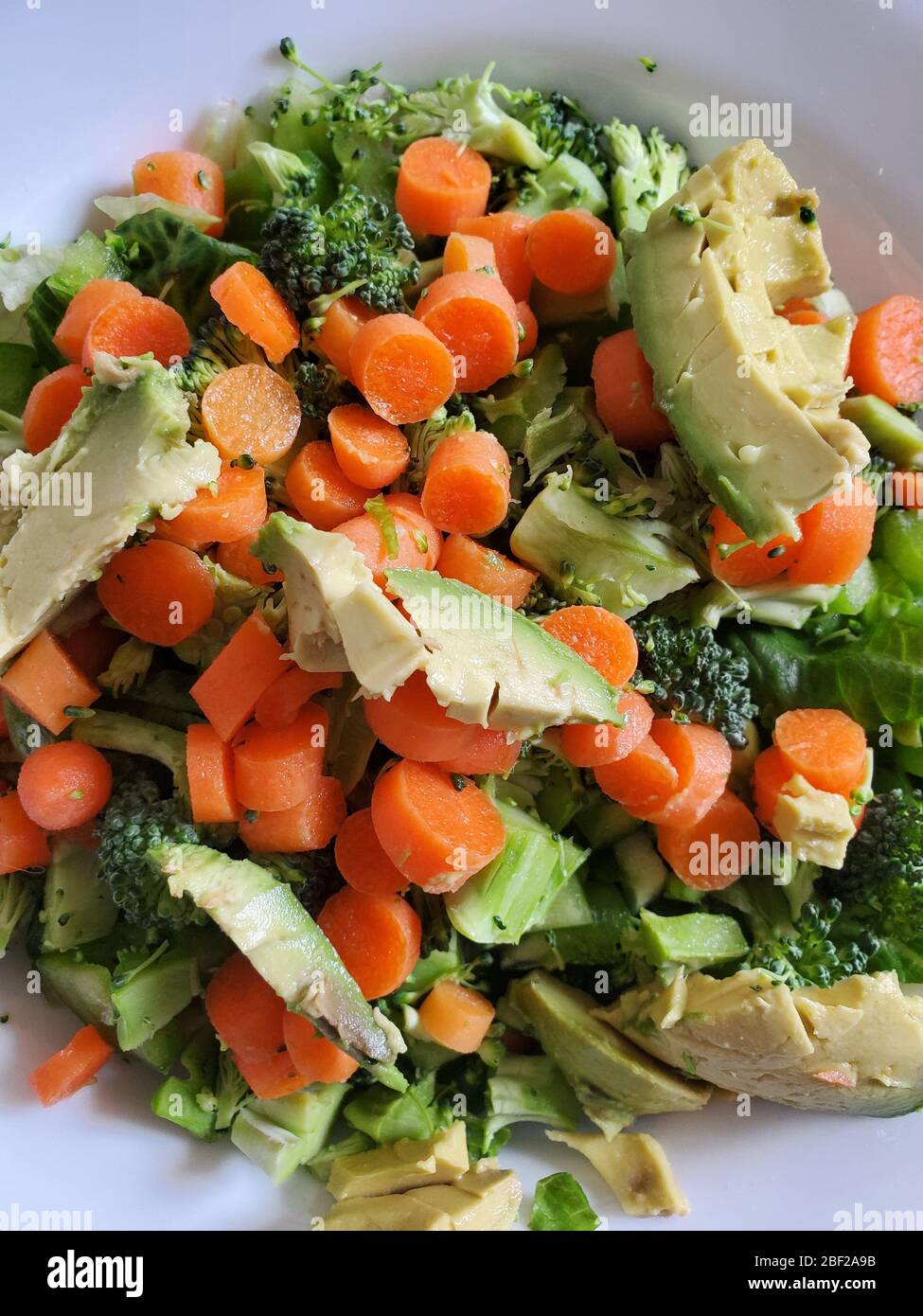 Un tazón de ensalada de verduras saludables en un tazón blanco Foto de stock
