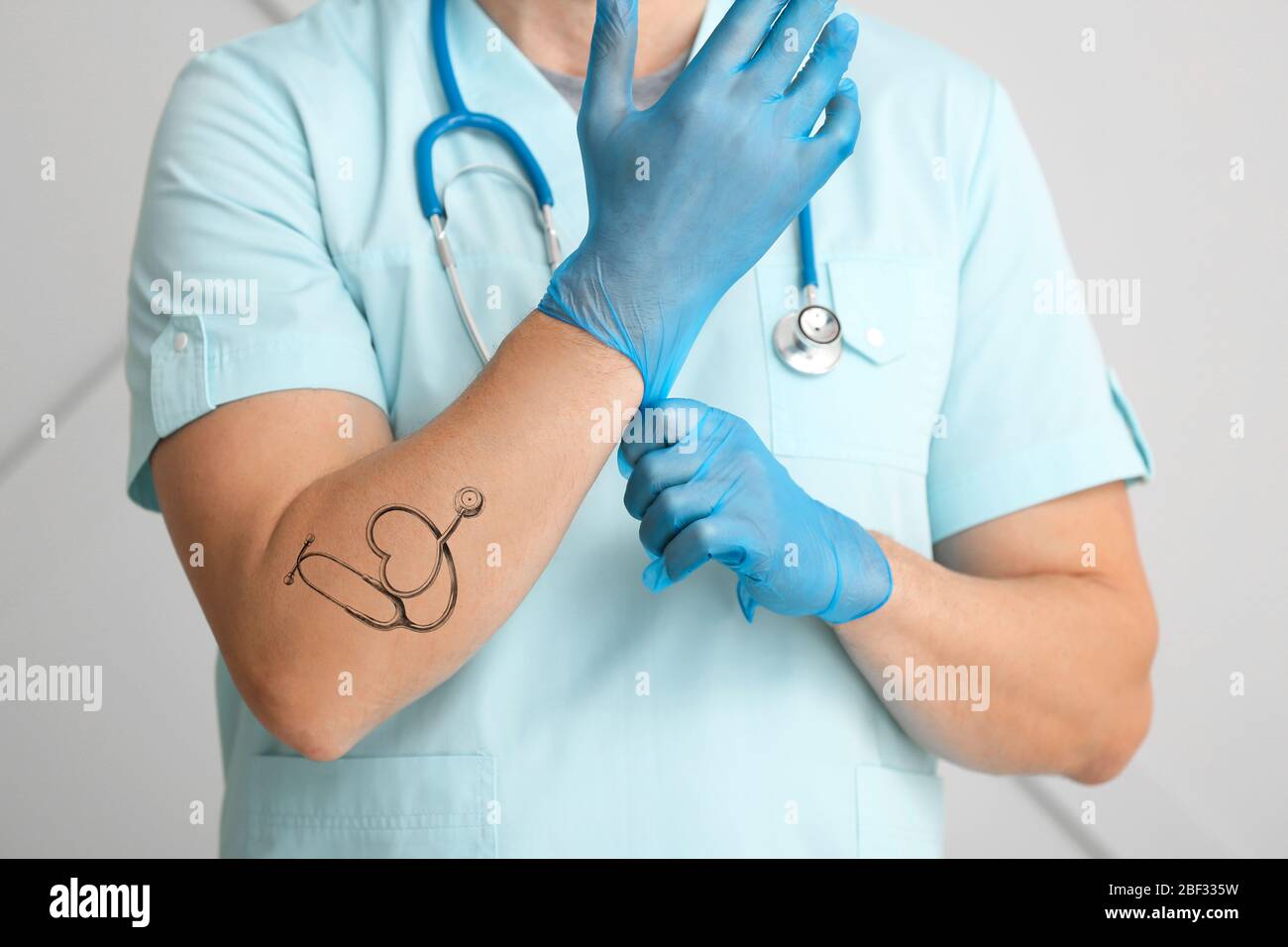 Médico masculino con tatuaje de estetoscopio en el brazo usando guantes, cierre Fotografía de stock - Alamy