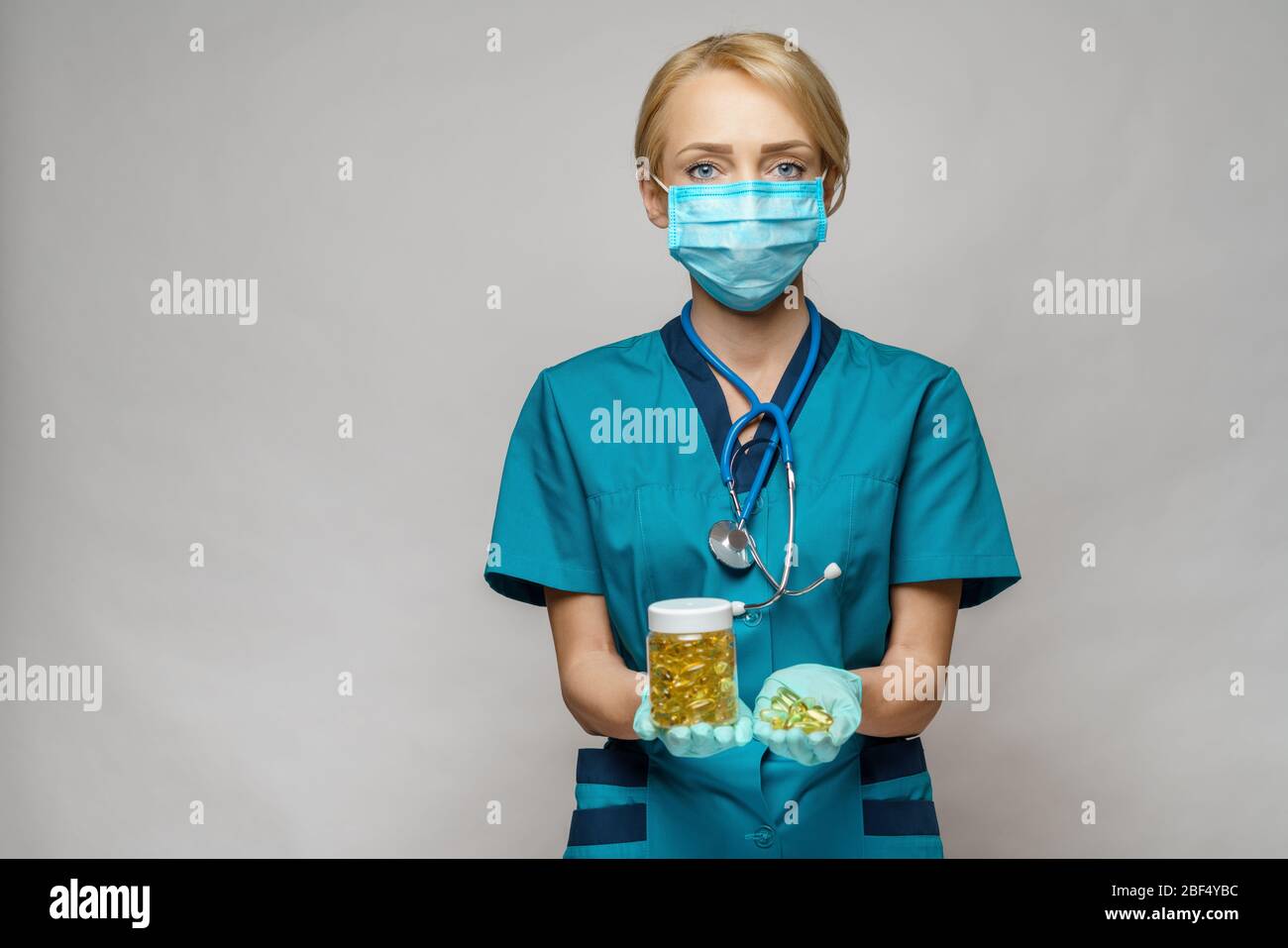 médico enfermera mujer usando máscara protectora y guantes de goma o látex - sosteniendo lata de píldoras Foto de stock