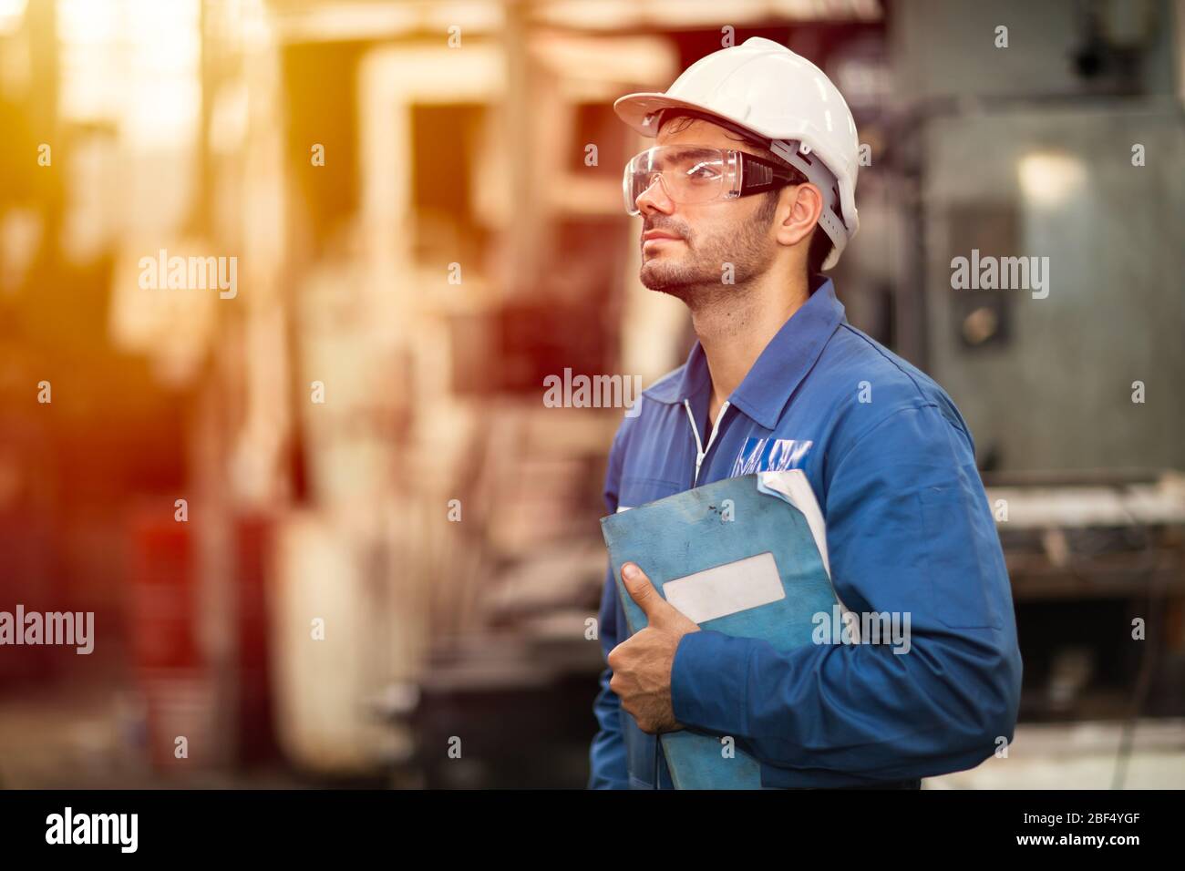 Retrato de ingeniero inteligente educación máquina manual de servicio libro trabajador feliz de pie orgulloso en la industria pesada antecedentes. Foto de stock