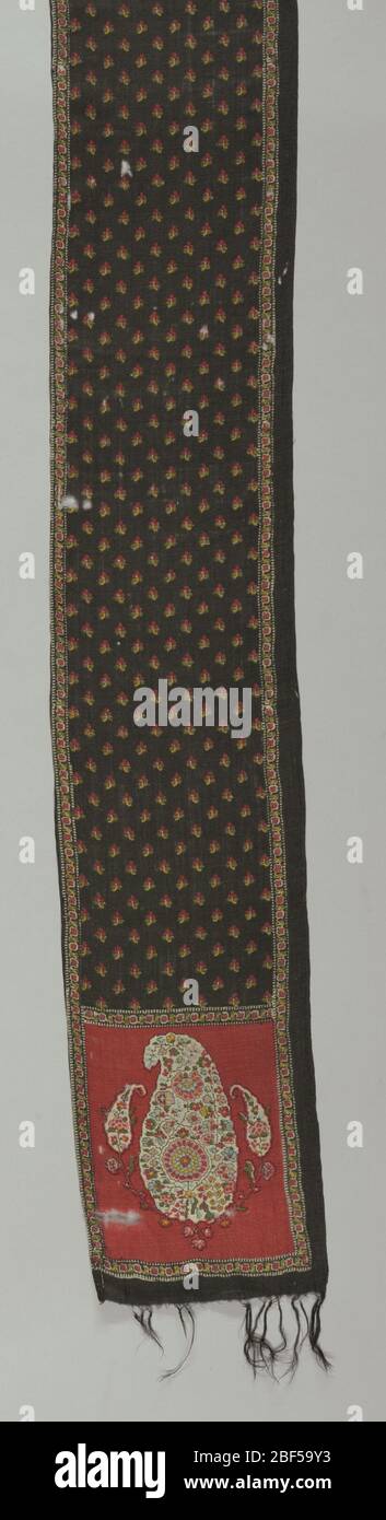 Bufanda. Bufanda de lana estampada; con flecos en los extremos; fondo negro en el cuerpo de la bufanda; fondo rojo en los extremos; estampado policromado en el patrón del cono persa; un borde largo con dobladillo. Foto de stock