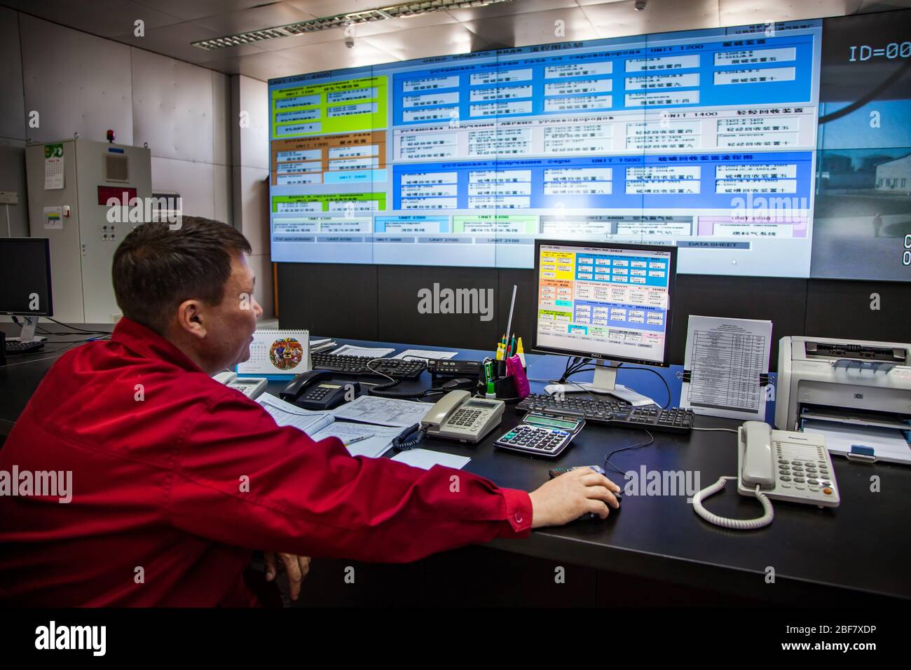 Planta de refinería de petróleo. Sala de control de funcionamiento (central). Operador en los procesos de monitorización del desgaste de trabajo rojo. Empresa CNPC. Foto de stock