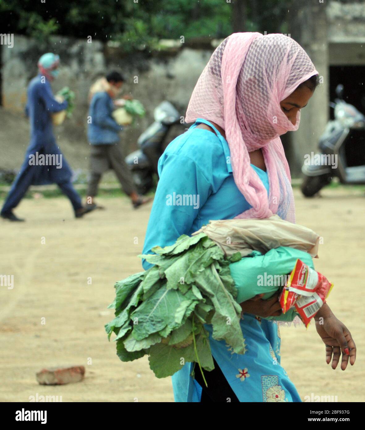 Jammu, Cachemira controlada por la India. 17 de abril de 2020. Una mujer lleva alimentos distribuidos por la policía durante el encierro para contener la propagación de un nuevo coronavirus, en Jammu, la capital de invierno de Cachemira controlada por la India, el 17 de abril de 2020. Crédito: Str/Xinhua/Alamy Live News Foto de stock