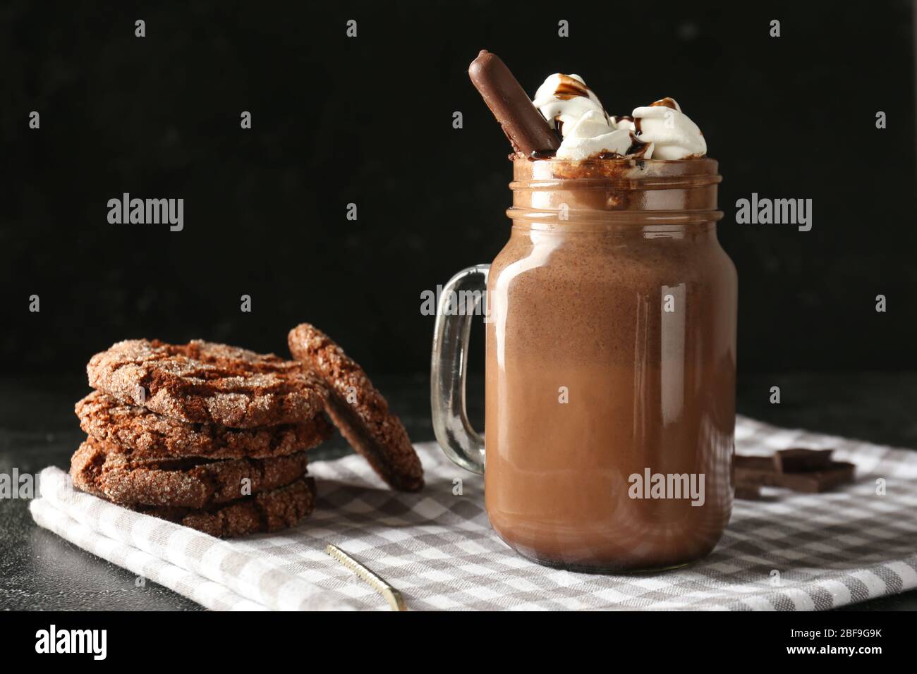 Tarro de chocolate caliente con galletas sobre fondo oscuro Foto de stock